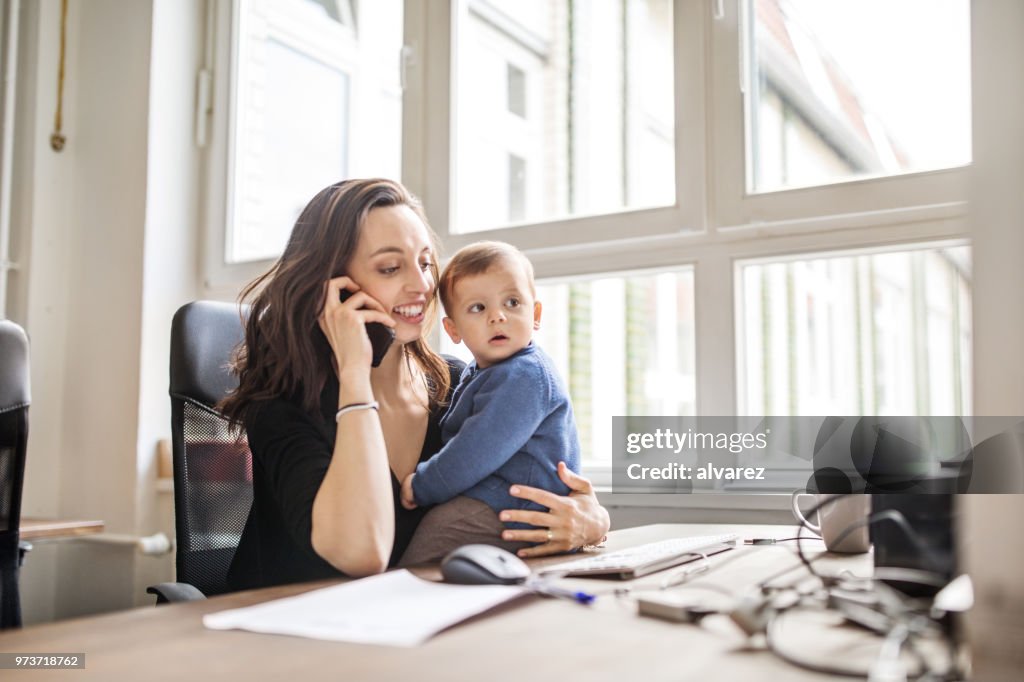 Single mother with son working in office