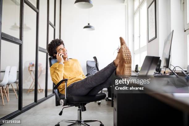 relaxed businessman talking on phone in office - feet up stock pictures, royalty-free photos & images