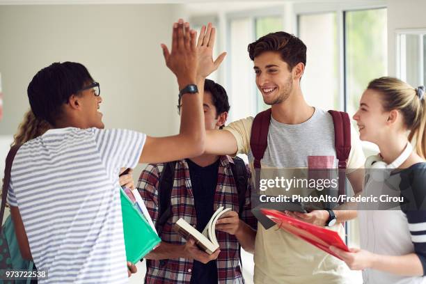 students giving each other a high-five in corridor - hi 5 stock pictures, royalty-free photos & images