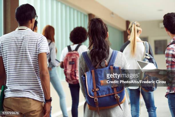 students walking in school corridor, rear view - sekundarstufe stock-fotos und bilder
