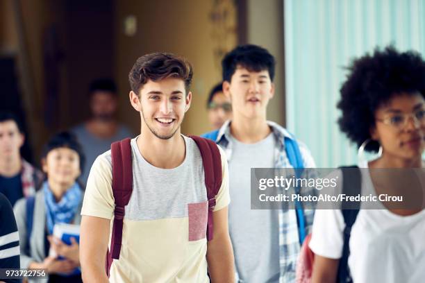 student smiling as he walks between classes - femme entre deux hommes photos et images de collection