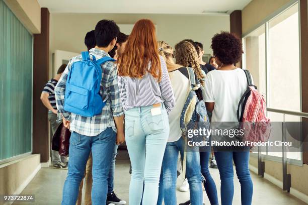 group of students standing in school corridor, rear view - jeans back stockfoto's en -beelden