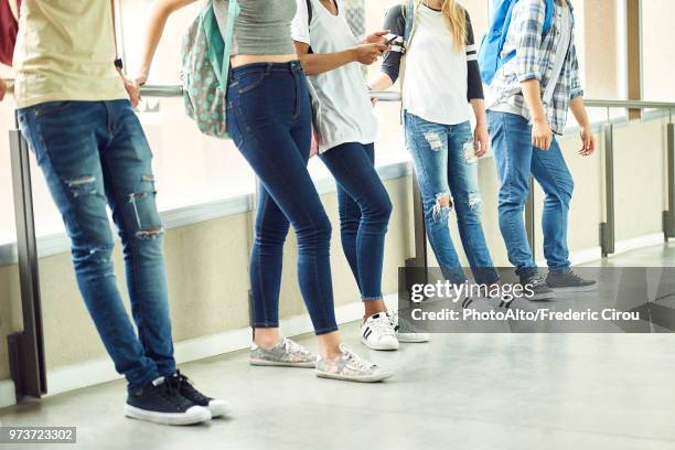 casually dressed students leaning against railing in school corridor between classes - calças justas - fotografias e filmes do acervo