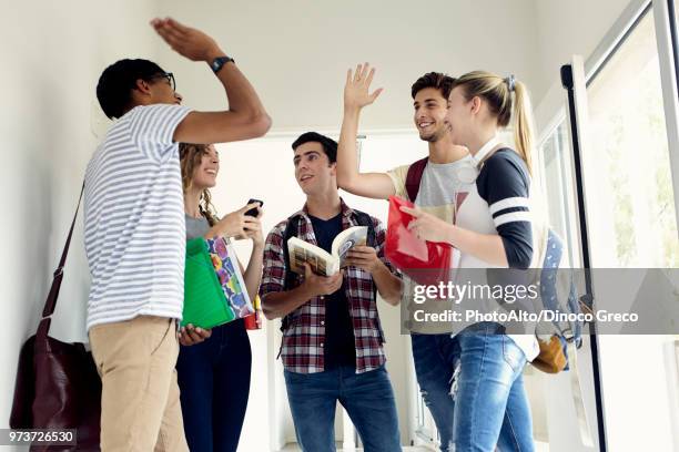 students giving each other a high-five in corridor - black man high 5 stockfoto's en -beelden