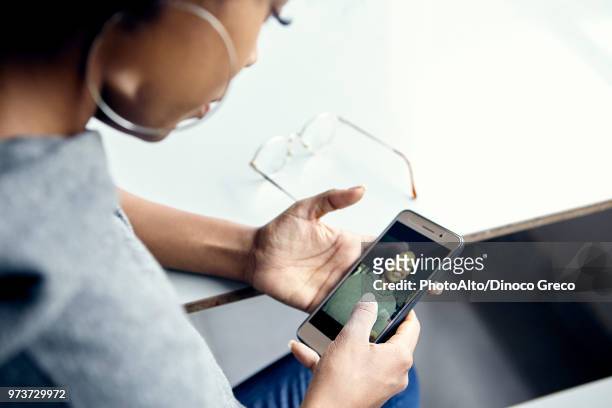 young woman looking photograph of herself on smartphone - black woman looking over shoulder stock pictures, royalty-free photos & images
