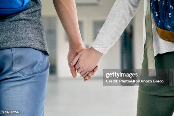 couple holding hands in corridor, cropped - couple school stockfoto's en -beelden