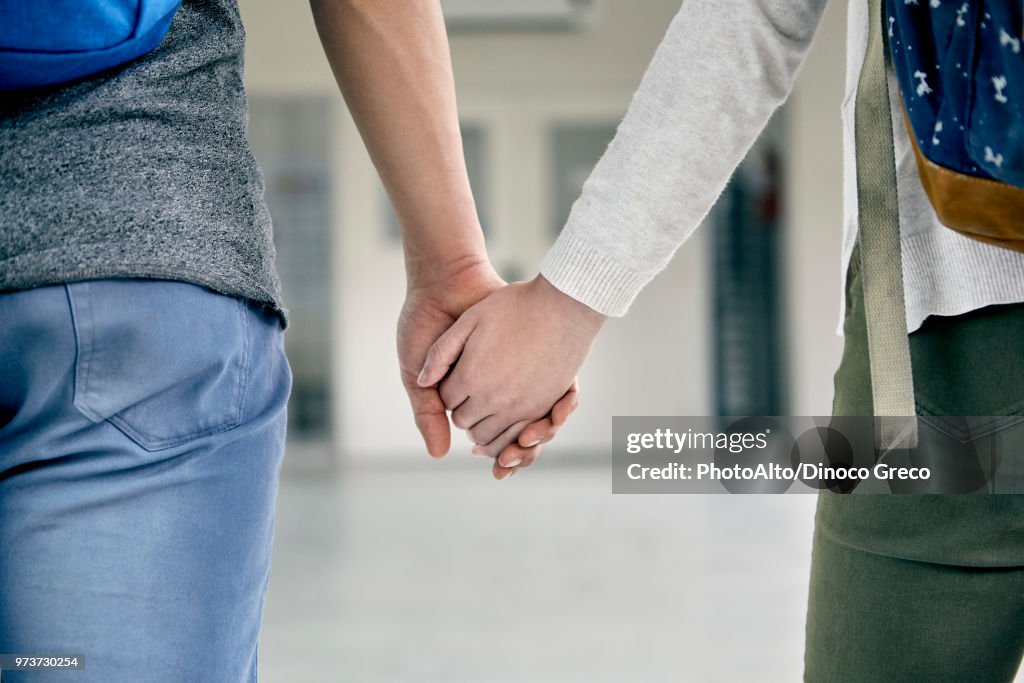 Couple holding hands in corridor, cropped