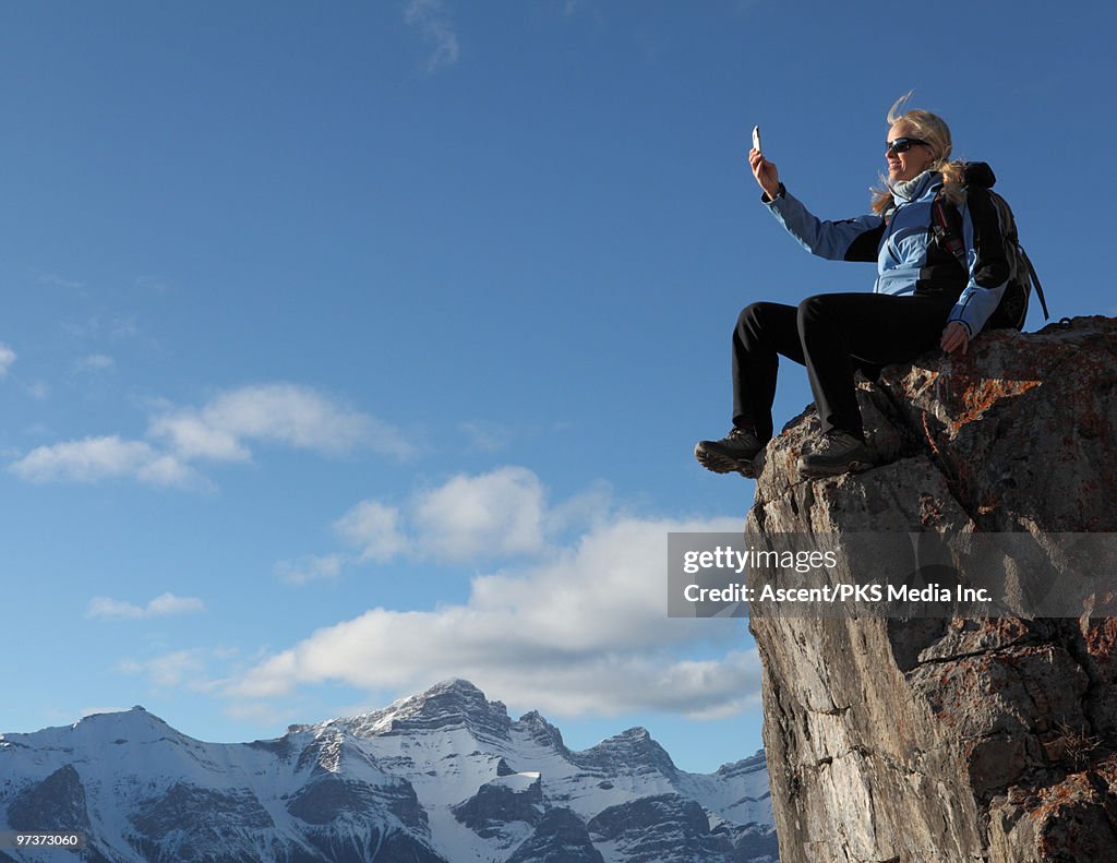 Hiker takes picture with cell phone, mtn summit