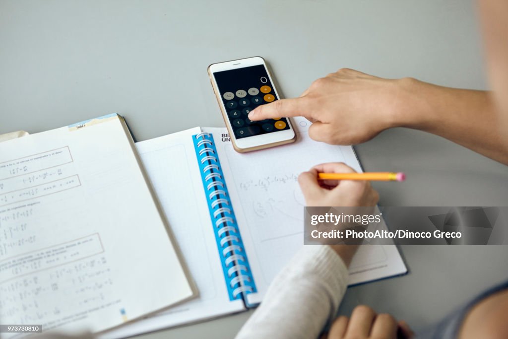 Students using smartphone calculator function while completing math assignment