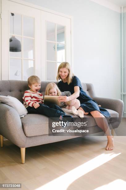 moeder en haar kinderen met behulp van digitale tablet pc in de woonkamer - living room kids stockfoto's en -beelden