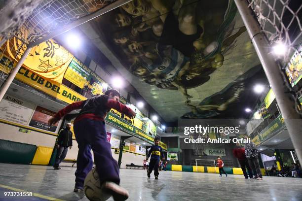 Kids play at the 5-a-side pitch of Sportivo Pereyra de Barracas club on June 13, 2018 in Buenos Aires, Argentina. The mural was painted in the...