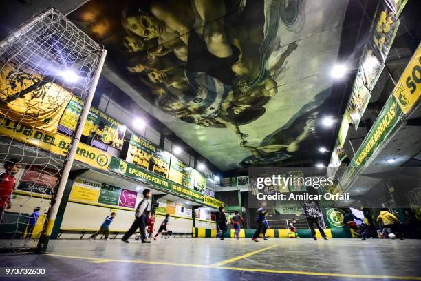 Kids play at the 5-a-side pitch of Sportivo Pereyra de Barracas club on June 13, 2018 in Buenos Aires, Argentina. The mural was painted in the...