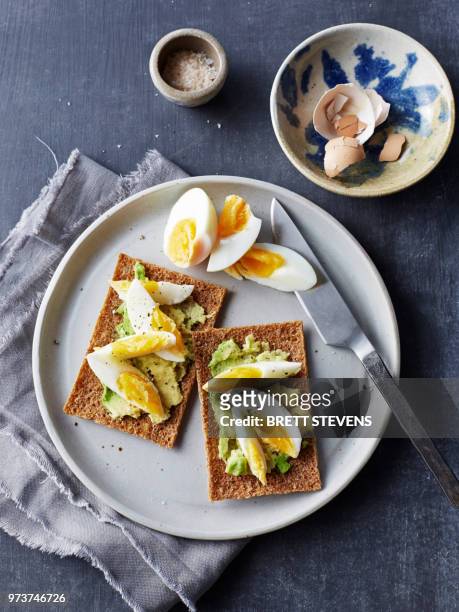 still life of rye crackers with boiled sliced eggs on plate, overhead view - hard boiled eggs stock-fotos und bilder