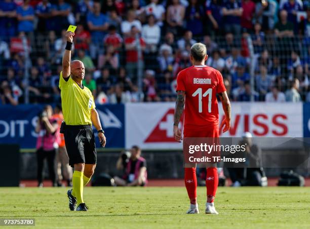 Referee Amaury Delerue shows a yellow card to Valon Behrami of Switzerland during the international friendly match between Switzerland and Japan at...