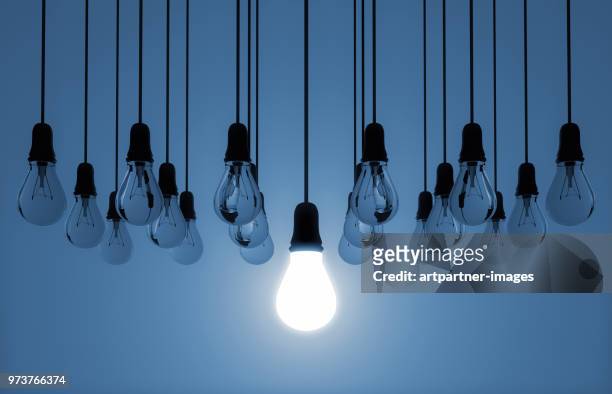 hanging light bulb switched on - estrategia fotografías e imágenes de stock