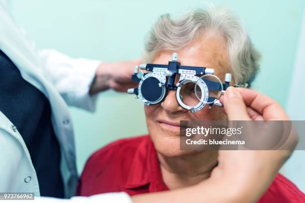 senior woman having her eyes checked at ophthalmologist - astigmatism stock pictures, royalty-free photos & images