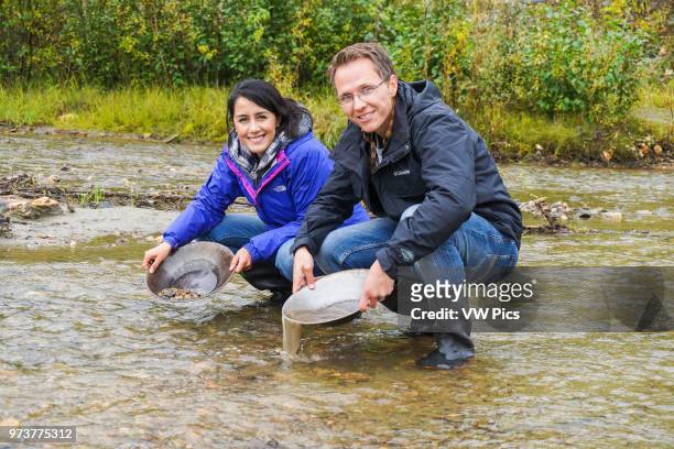 Man and female couple go gold panning in the Yukon.