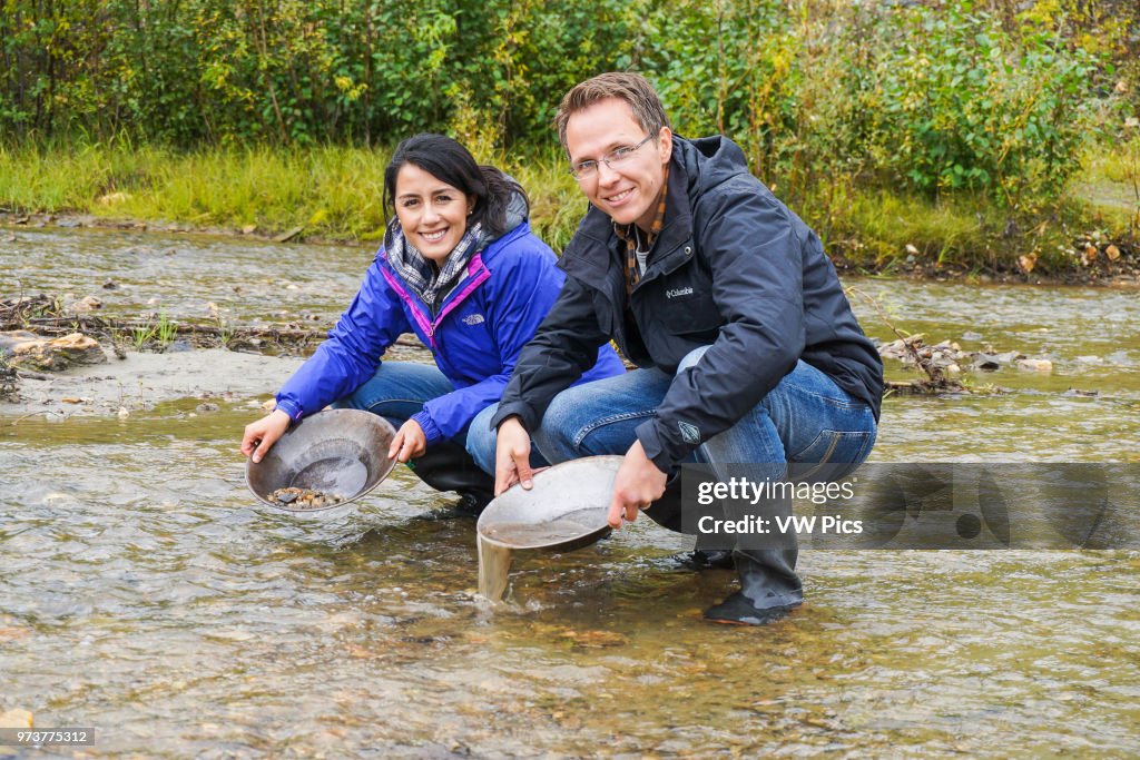 Man and female couple go gold panning in the Yukon.