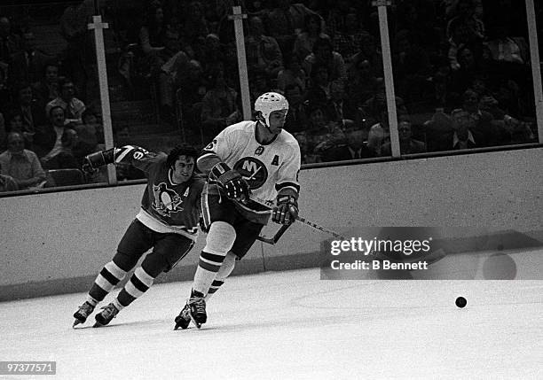 Bert Marshall of the New York Islanders skates with the puck as Syl Apps of the Pittsburgh Penguins persues during Game 3 of the Quarter-Finals on...