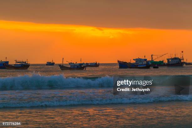 orange dawn at beach with many fishing boats - jethuynh stock pictures, royalty-free photos & images