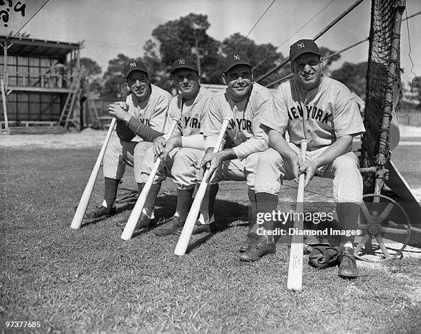 Outfielders Joe DiMaggio, Nick Etten, Charlie Keller and Tommy Henrich of the New York Yankees pose for a portrait while sitting on the back of the...