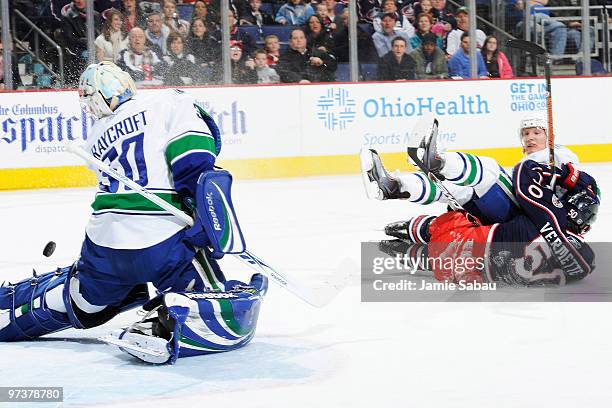 Antoine Vermette of the Columbus Blue Jackets beats goaltender Andrew Raycroft of the Vancouver Canucks as he is knocked over by Christian Ehrhoff of...