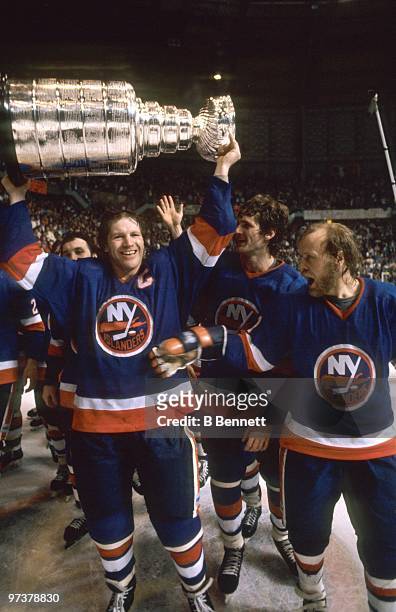 Captain Denis Potvin of the New York Islanders hoists the Stanley Cup as teammate Butch Goring celebrates after winning the 1982 Stanley Cup Finals...