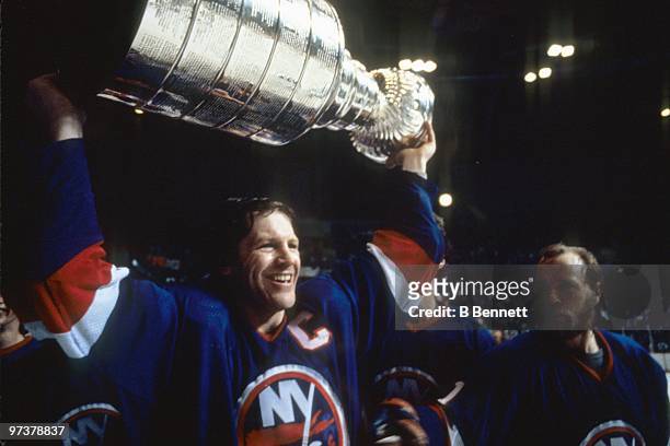Captain Denis Potvin of the New York Islanders hoists the Stanley Cup as teammate Butch Goring looks on after winning the 1982 Stanley Cup Finals...