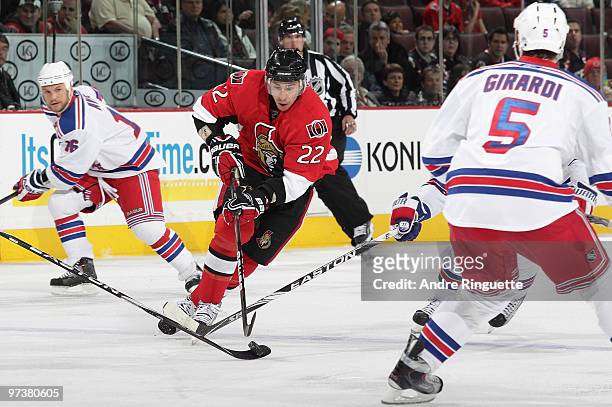 Chris Kelly of the Ottawa Senators stickhandles the puck against Sean Avery and Daniel Girardi of the New York Rangers at Scotiabank Place on March...