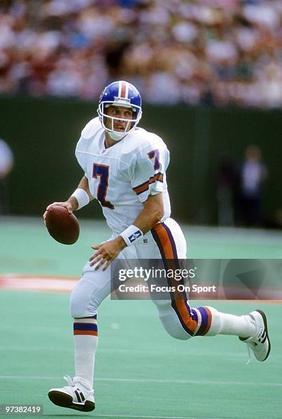 S: Quarterback John Elway of the Denver Broncos scrambles with the ball while looking down frield for a receiver against the New York Jets circa...