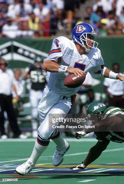 S: Quarterback John Elway of the Denver Broncos scrambles with the ball while looking down frield for a receiver against the New York Jets circa...