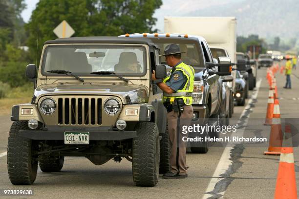 Colorado State Patrol officer Jason Bandy talks to homeowners before allowing them to go through the road closure along Highway 550 on June 13, 2018...