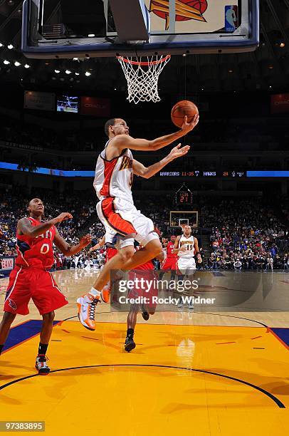 Stephen Curry of the Golden State Warriors shoots a layup against Jeff Teague of the Atlanta Hawks during the game at Oracle Arena on February 21,...