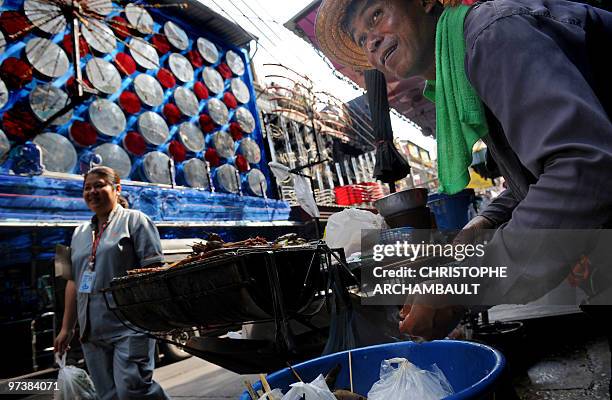 Man prepares skewers at his food stall at Soi Cowboy, one of Bangkok's red-light districts on March 3, 2010. Thailand's inflation rose for the fifth...