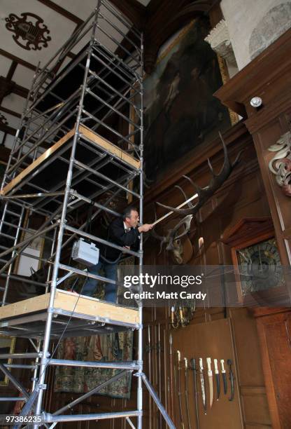 Longleat's house steward Steve Blyth cleans the 9ft wide prehistoric Giant Fallow Deer antlers that are displayed on the wall in Longleat House...