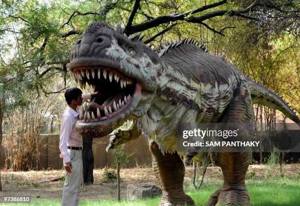 Indian Nature Educator Natwarsinh Rathod cleans the mouth of a Rajasaurus Narmadensis dinosaur model at the Indroda Dinosaur and Fossil Park in...