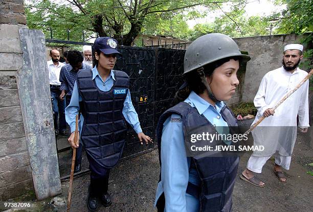 An Islamic student looks on as two Pakistani policewomen leave after conducting a search at the house of an Imam, who is wanted on suspicion of...