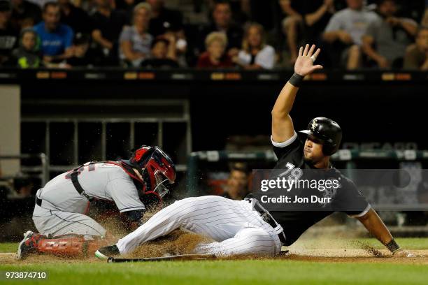 Jose Abreu of the Chicago White Sox slides safely to score on an RBI double hit by Kevan Smith as Roberto Perez of the Cleveland Indians is late with...