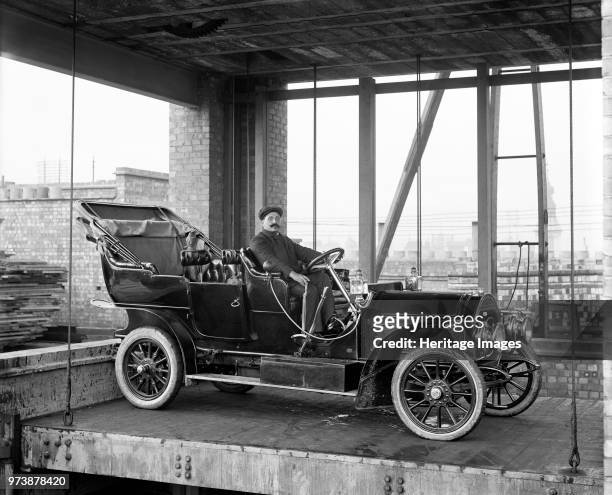 Car lift at Mitchell Motors Company, 114 Wardour Street, Westminster, London, 1907. An early motor car, with a chauffeur in the driver's seat on a...