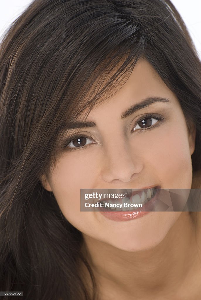 Ethnic young woman head shot smiling at camera.