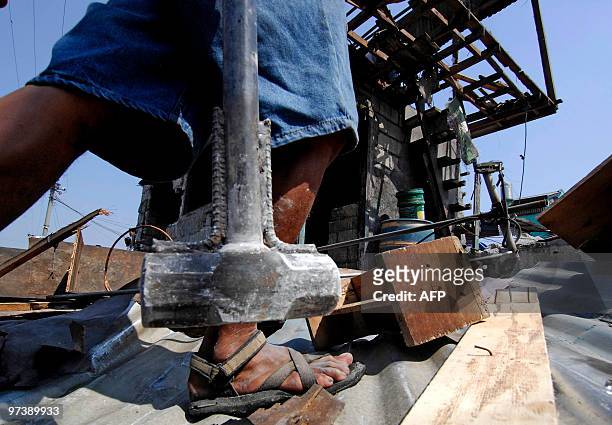Member of a demolition team carries a sledgehammer during operations in the Manila suburb of Navotas on March 2, 2010. Clashes broke out between...