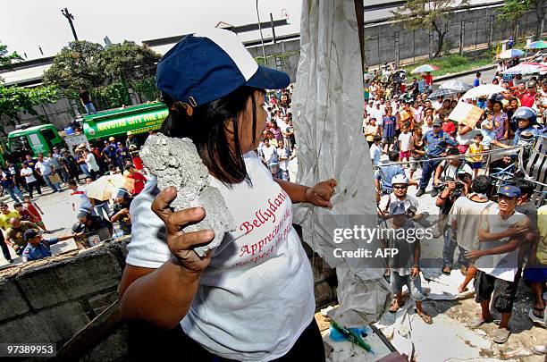 Resident threatens to throw a piece of concrete at members of a demolition team during a confrontation in the Manila suburb of Navotas on March 2,...