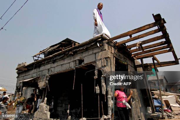 Controversial Roman Catholic priest Robert Reyes stands on the roof-top of a nearly demolished home to defend the residents during a demolition...