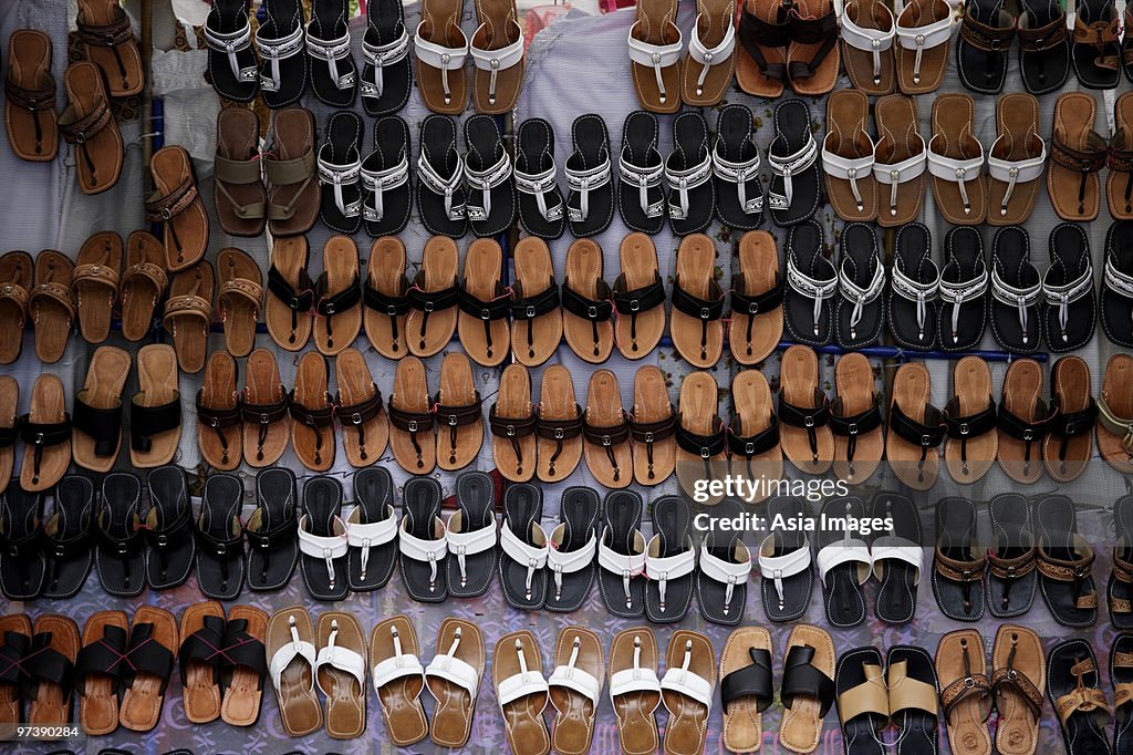 Many leather sandals on display at market.