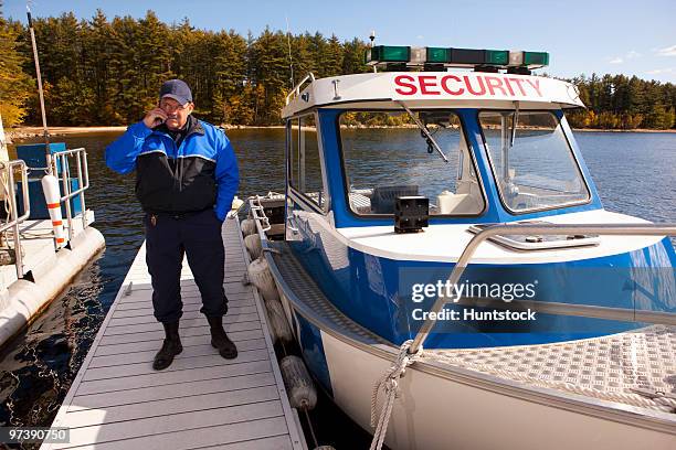 watershed security guard talking on a mobile phone at a dock - beschützer stock-fotos und bilder