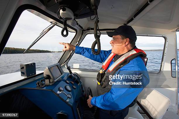 security guard controlling a boat for watershed security - flytväst bildbanksfoton och bilder
