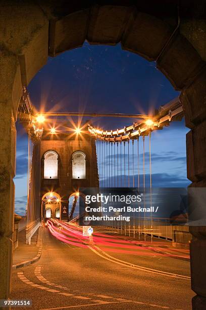 view along the a5 road at night across the menai suspension bridge, built by thomas telford in 1825, bangor, gwynedd, north wales, united kingdom, europe. - menai suspension bridge ストックフォトと画像