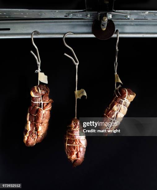 three cuts of lamb bresaola hanging to dry. - bresaola stock-fotos und bilder