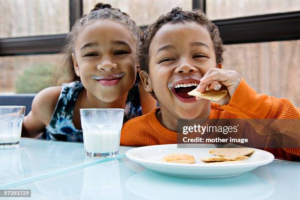 pre teen african american siblings snacking - milk family stockfoto's en -beelden