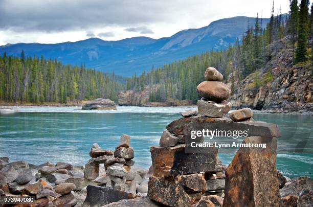 stacks of stones near river, athabasca falls, jasper national park, alberta, canada - athabasca river stock pictures, royalty-free photos & images